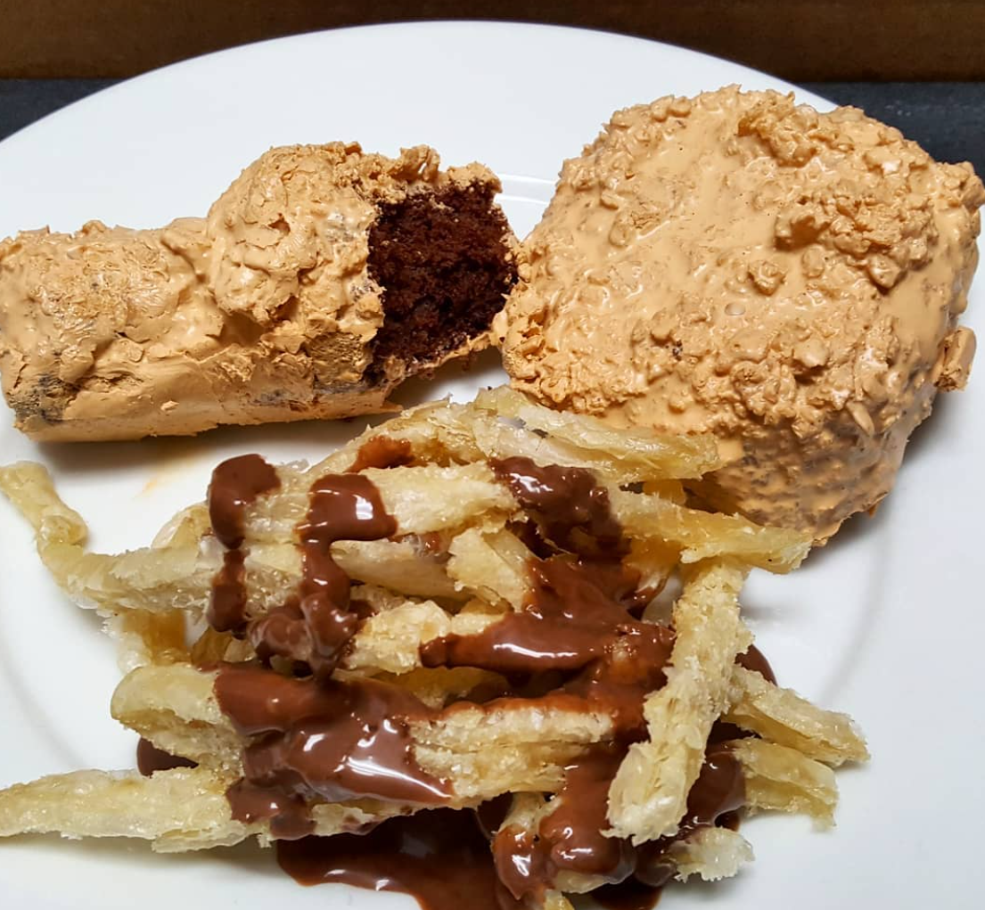 Fried chicken made of cake on a white plate with fries and gravy, from chefbenchurchill instagram