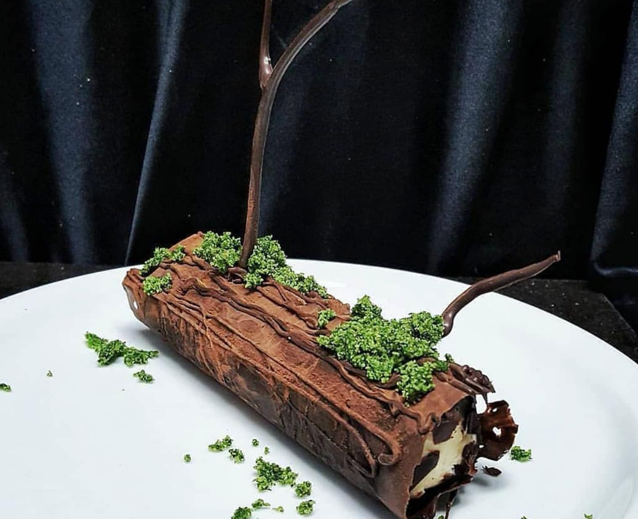 Mossy log cake on a white plate, by chefbenchurchill on instagram