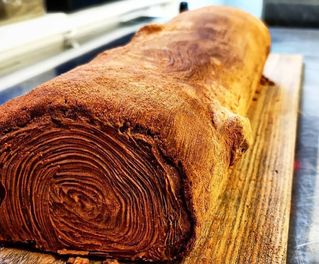 Yule log on a wooden cutting board, made of dessert, by chefbenchurchill on instagram