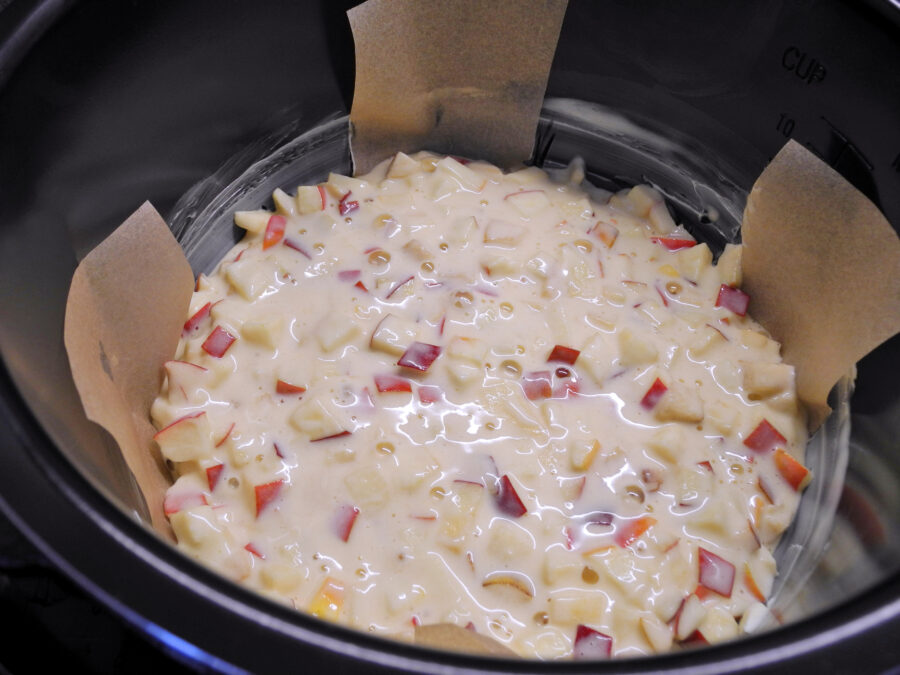 View of slow cooker apple pot pie before cooking. Biscuit dough with chopped apples.