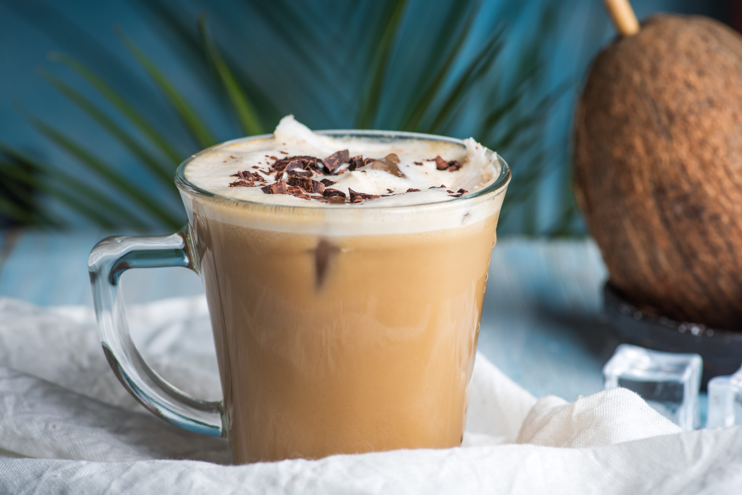 Coconut milk latte coffee decorated with grated chocolate in a modern glass cup closeup