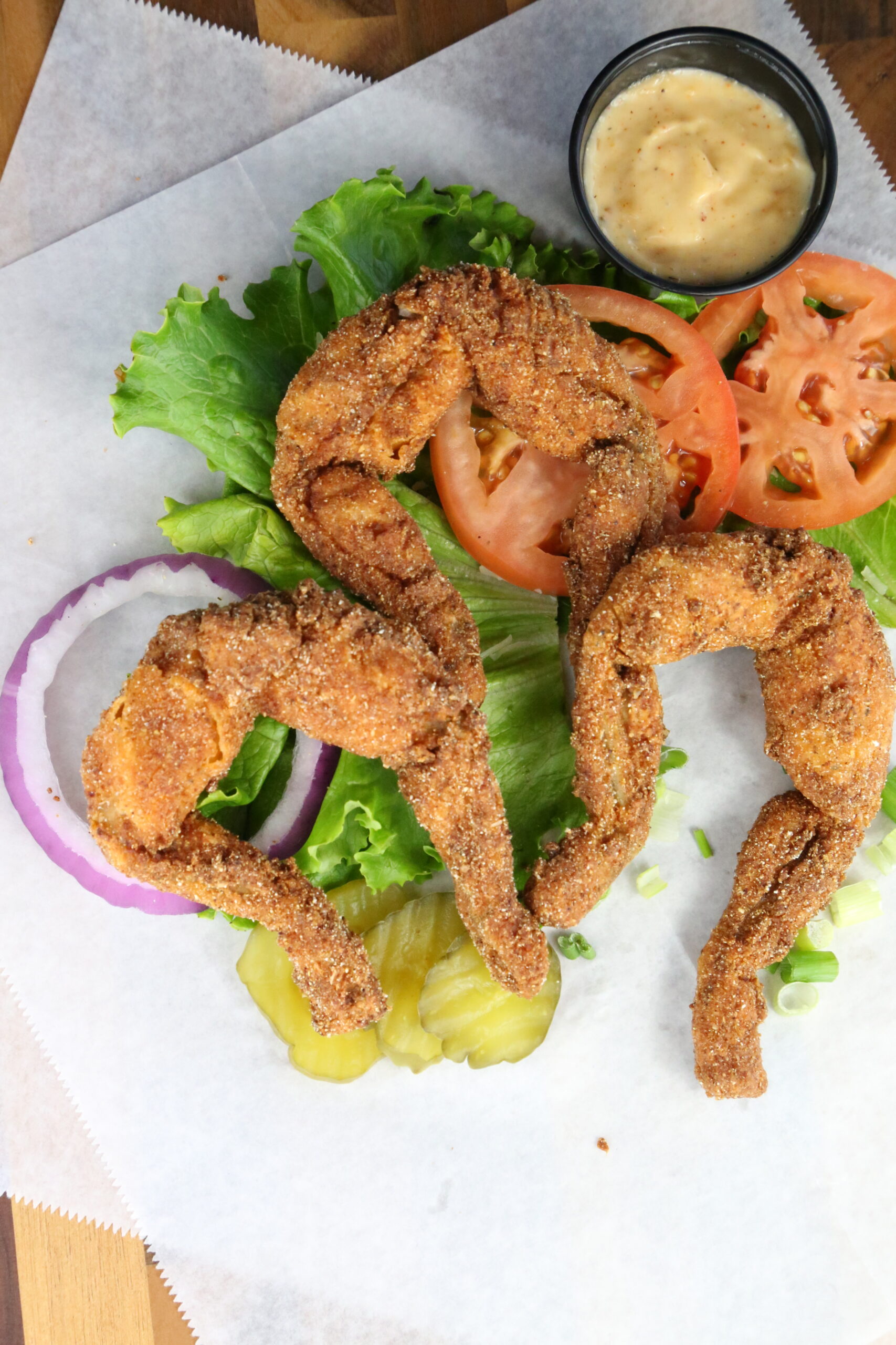 Frog Legs. Cajun Fried Frog Legs on a bed of lettuce, onions, and pickles.