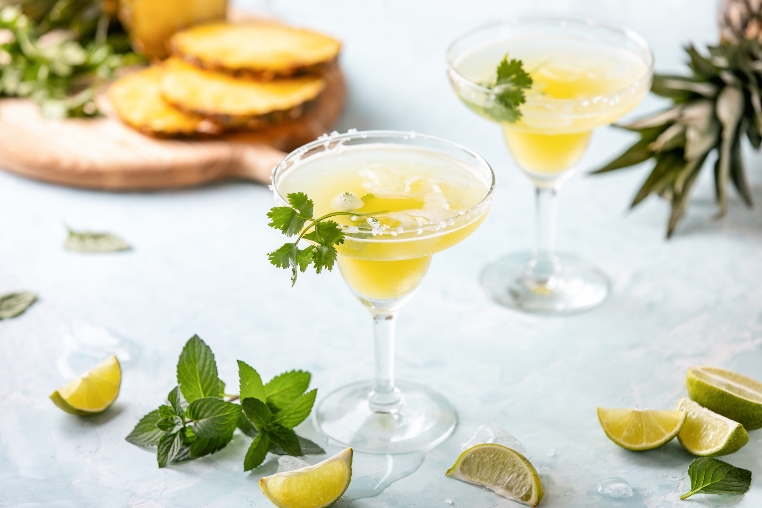 Pineapple coriander infused margarita in glasses with ingredients, front view