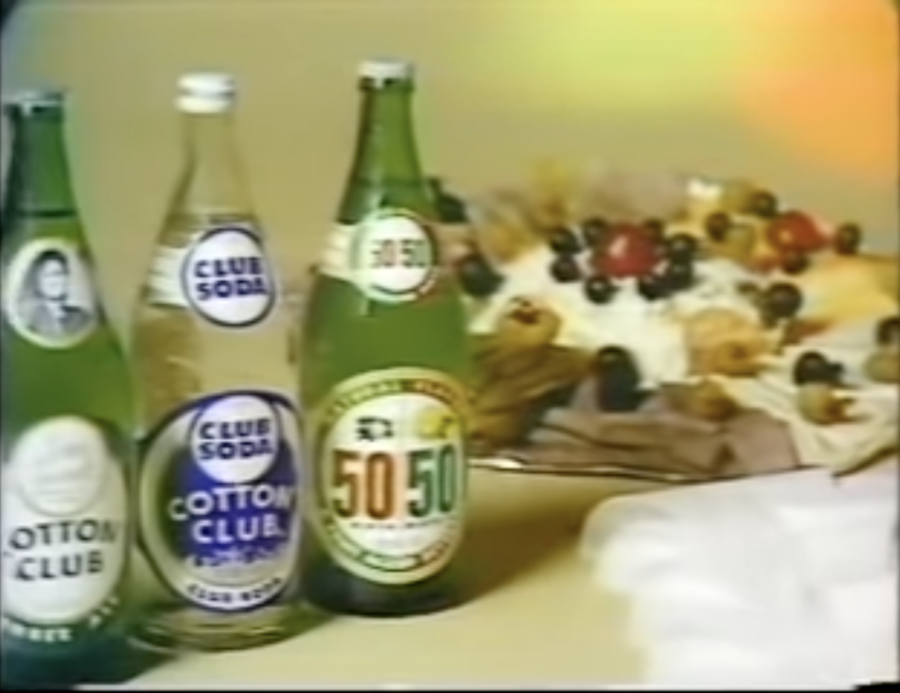 Bottles of Cotton Club soda in front of a cake, from 1977 commercial, posted to YouTube by commercials classics 1975 - 1985 