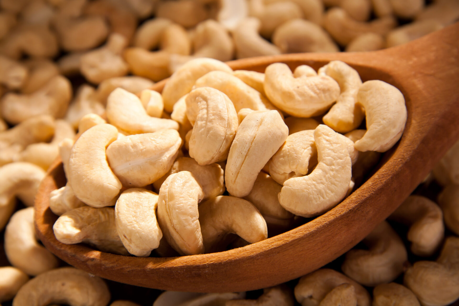 Close-up of cashews in a wooden spoon illustrating tree nut allergen risk.
