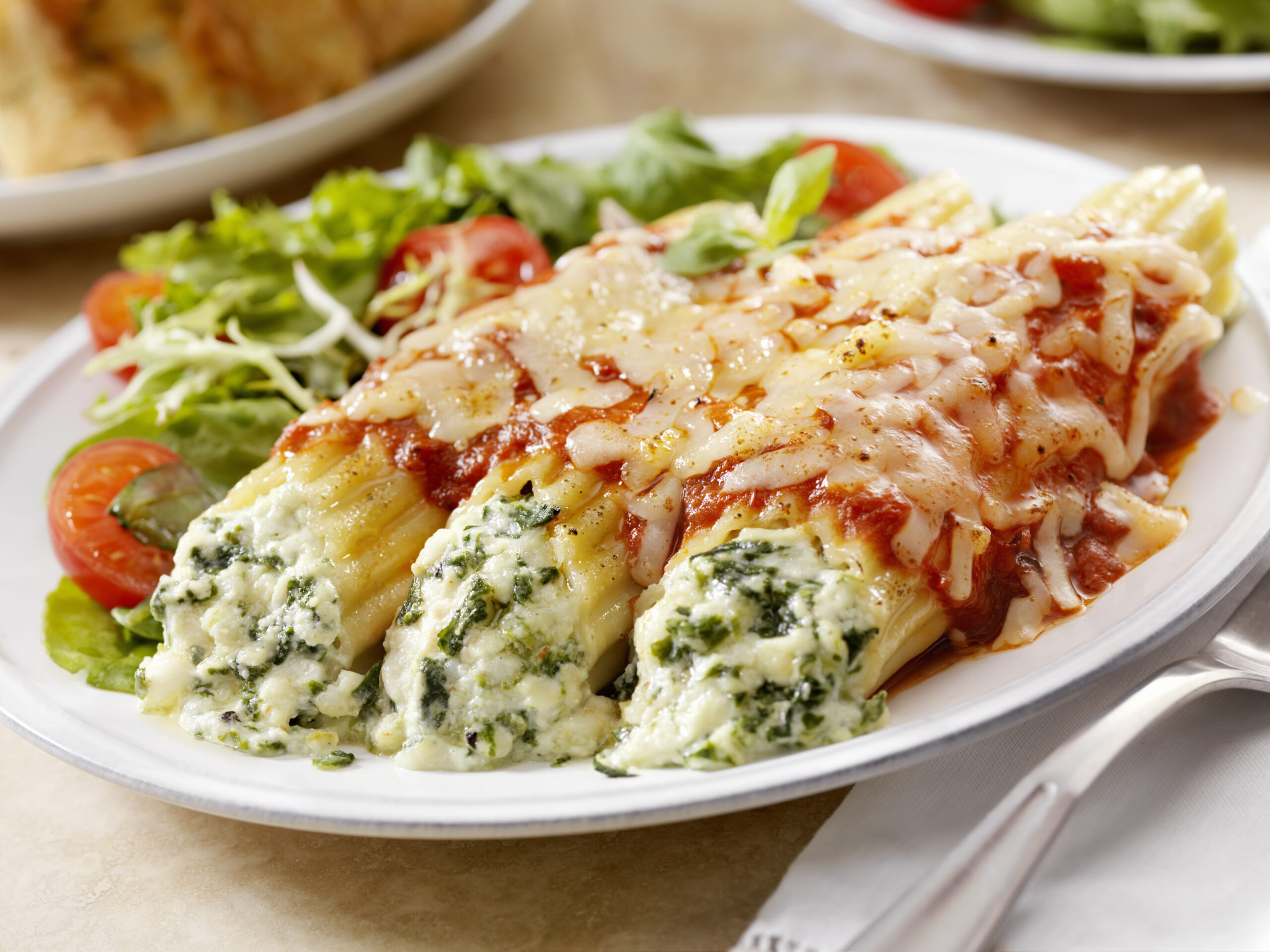 Authentic Italian Stuffed Manicotti with Ricotta and Spinach topped with a Tomato sauce and Mozzarella Cheese with a side Salad and Garlic Bread -Photographed on Hasselblad H3D2-39mb Camera