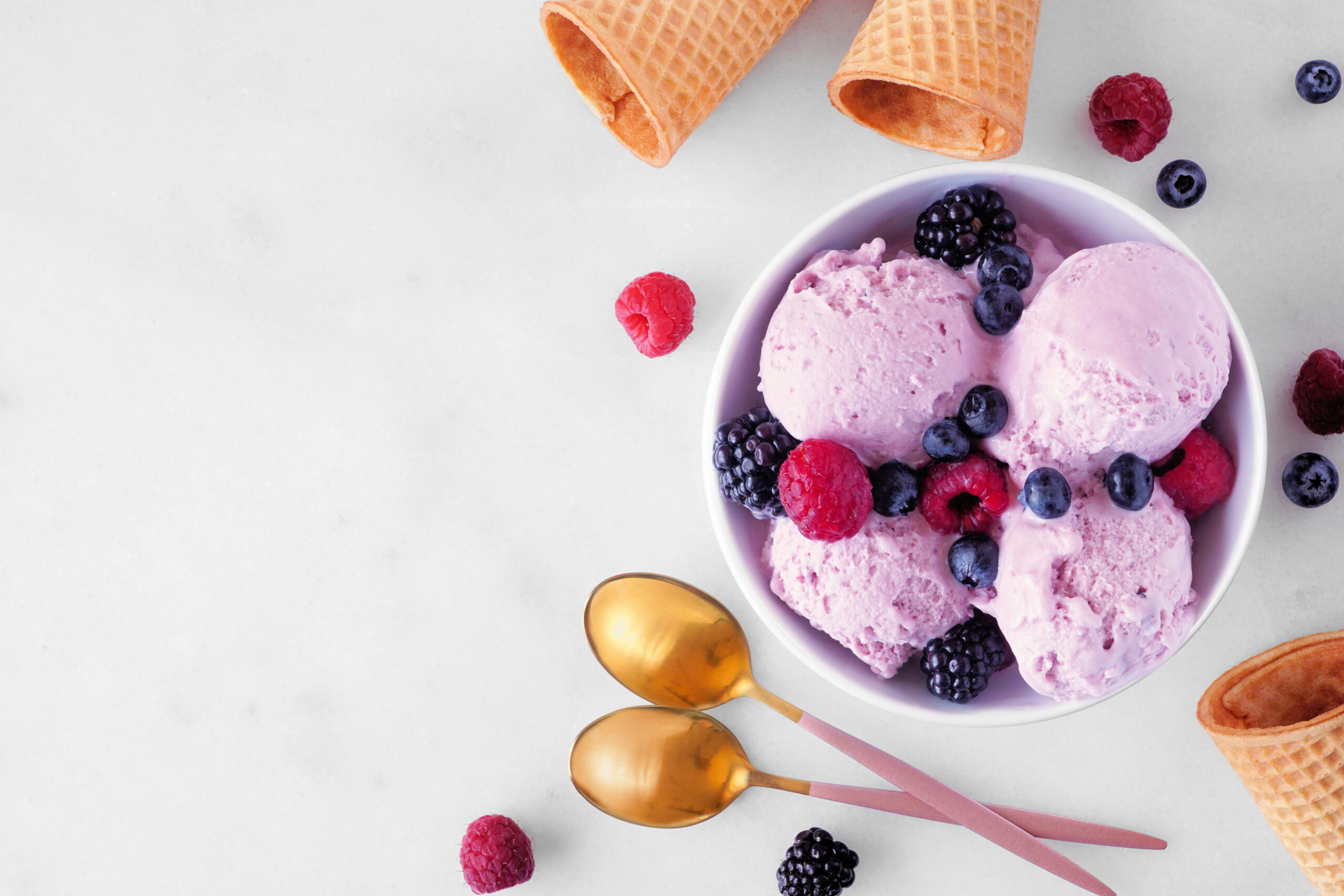 Bowl of field berry frozen yogurt. Top view table scene with copy space over a white marble background.