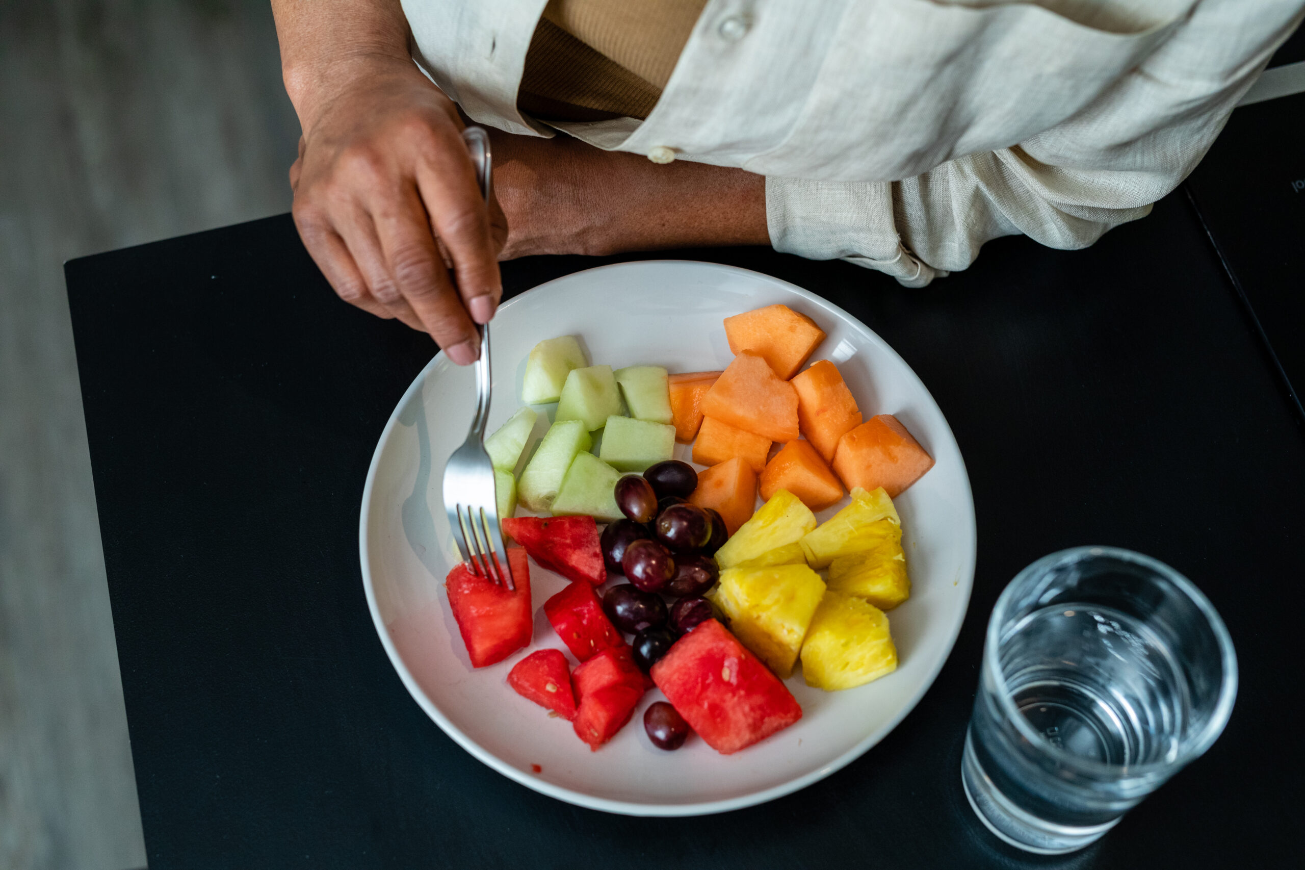 Elder black woman drinking wine and eating fruit in the kitchen