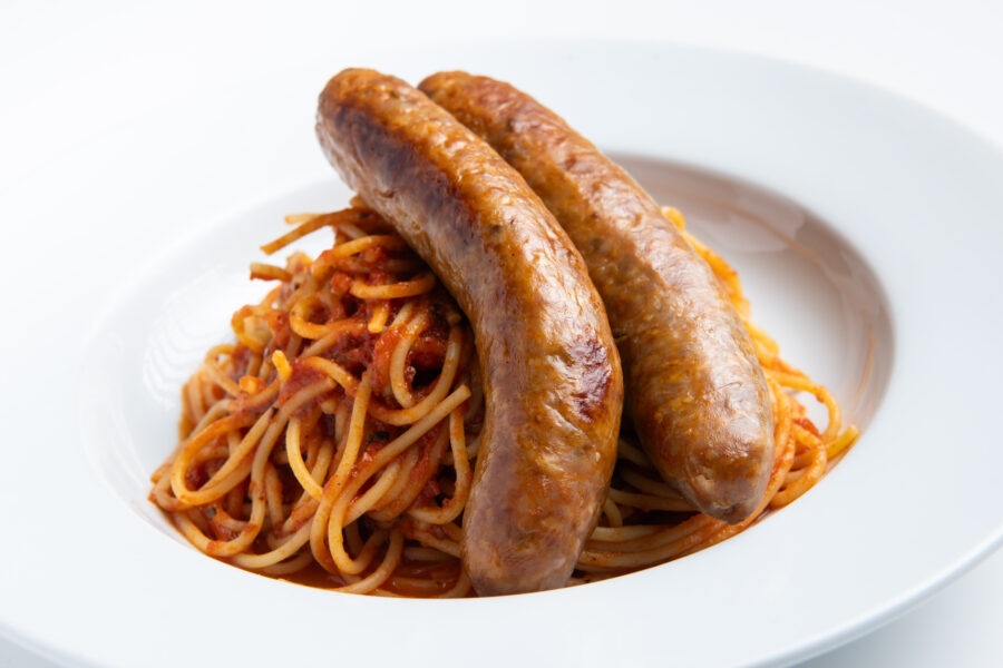 Grilled Italian sausages over Spaghetti Bolognese on white background