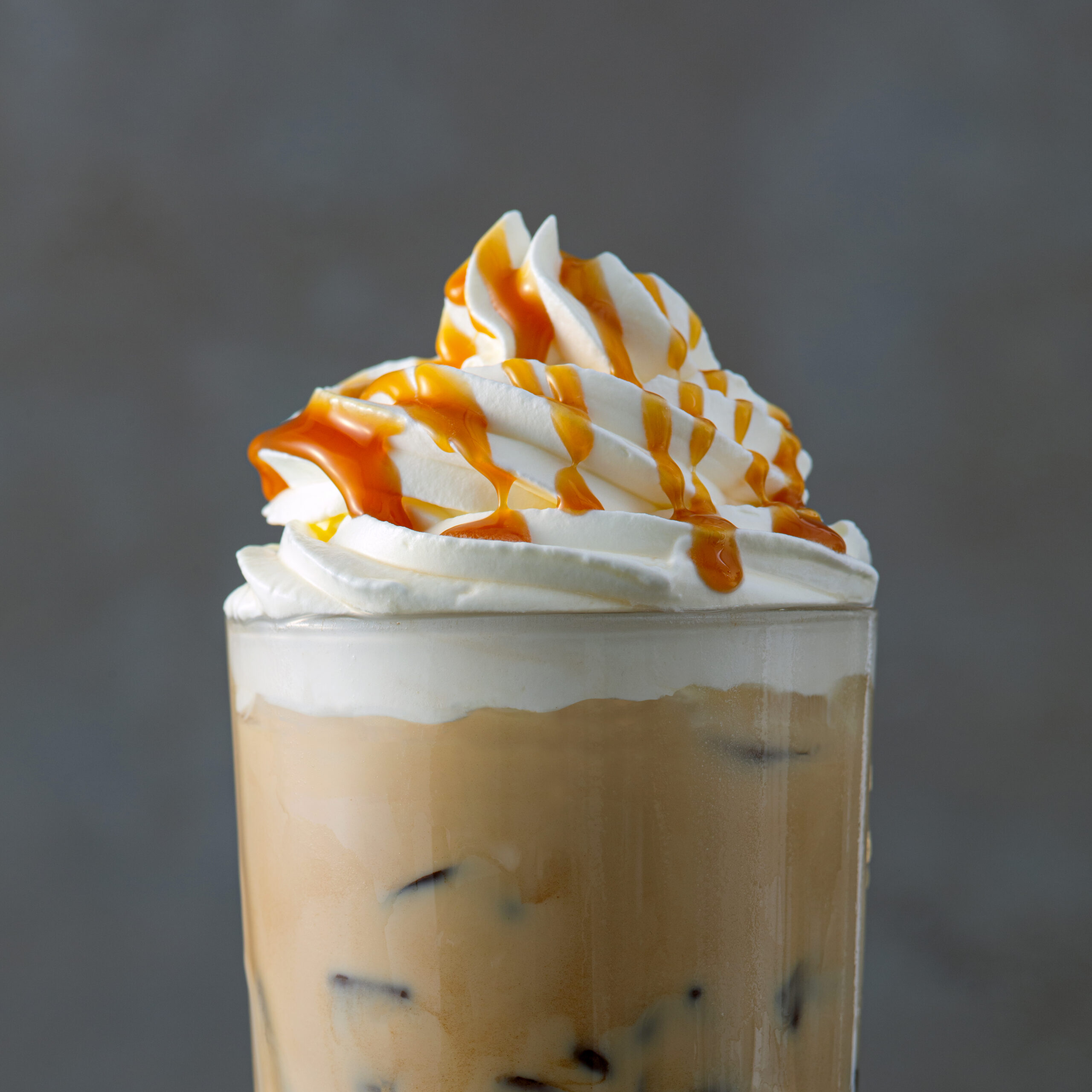 Caramel Frappe with whipped cream and caramel sauce on gray background