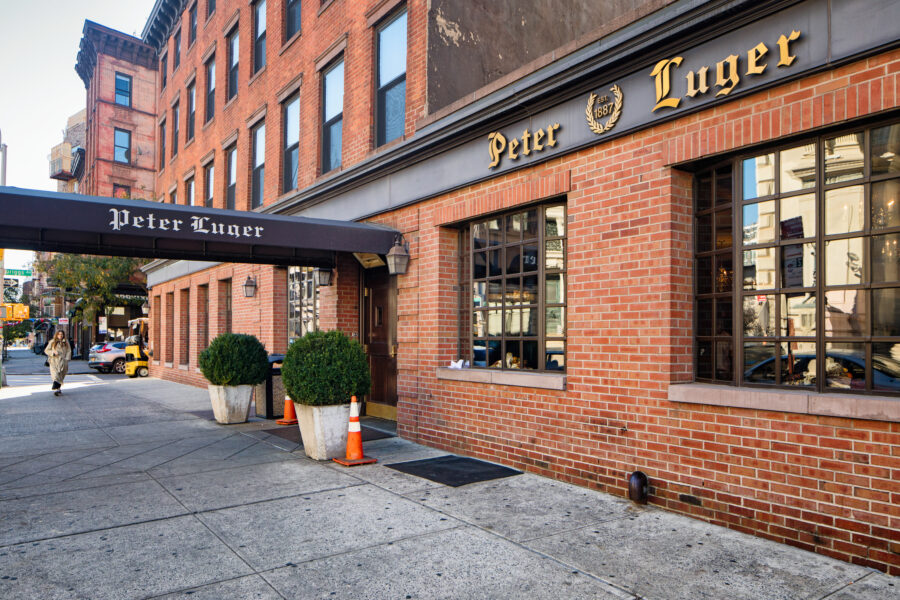 Peter Luger steak house in Williamsburg Brooklyn facade view with front door, awning and sidewalk.