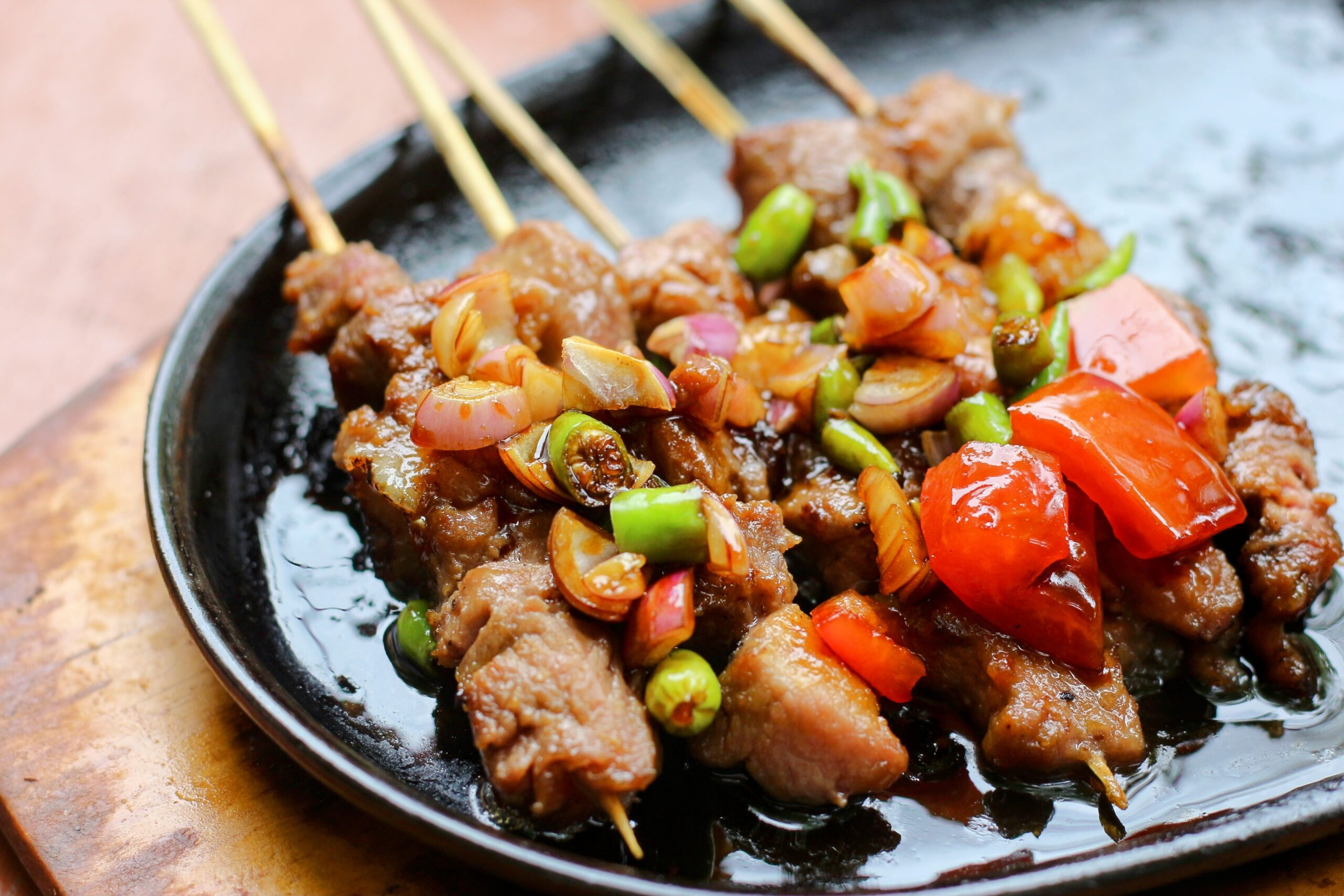 Goat Kebabs cooking with vegetables on a griddle stove top