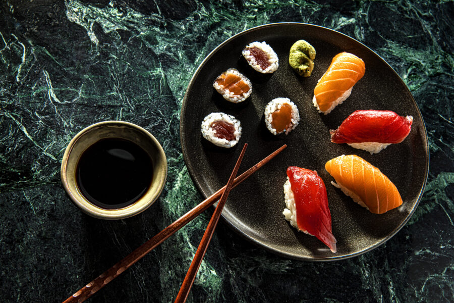 Set of sushi and maki with soy sauce over blue stone background. Top view with copy space