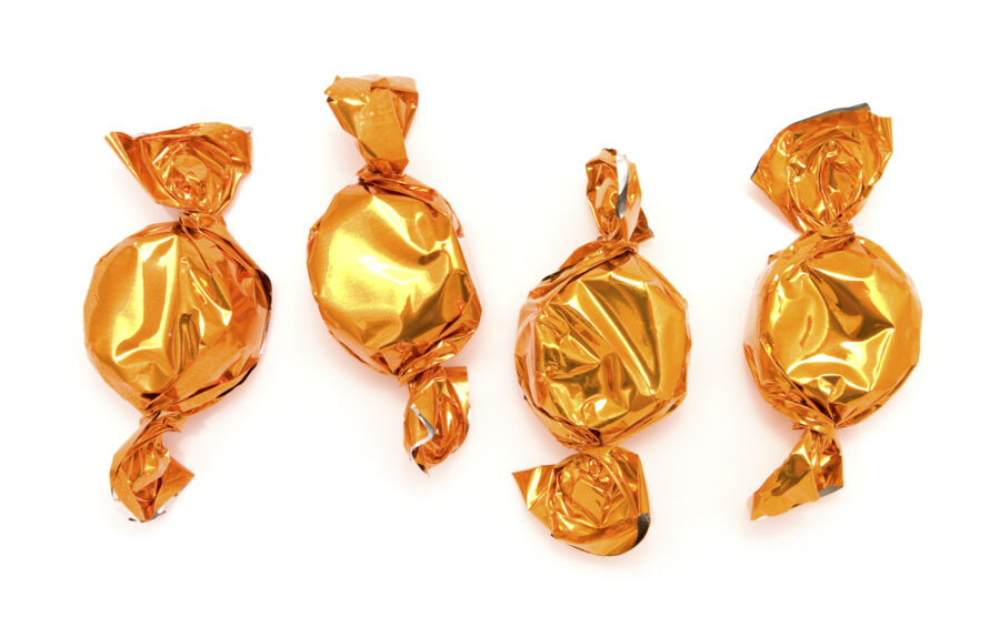 Sweets in orange foil wrappers on a white background