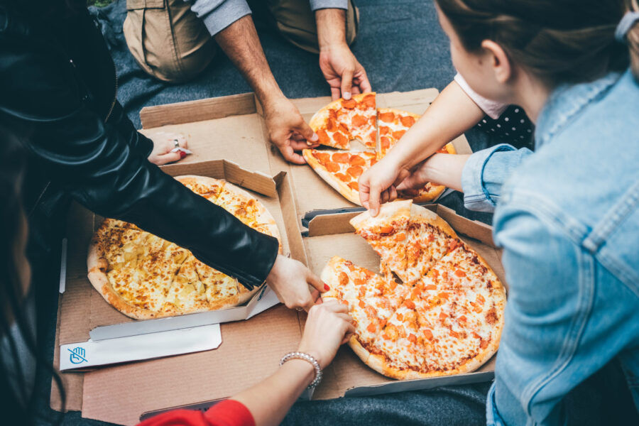 people grabbing pizza slices