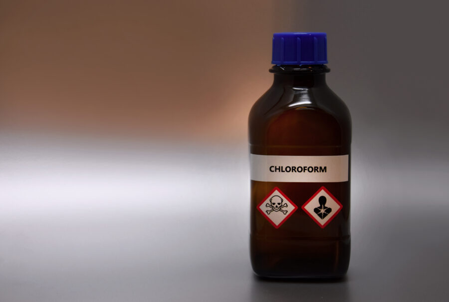 A bottle of chloroform with inscription. Brown lab bottle. Brown glass container. Phial with warning pictograms on a silver background