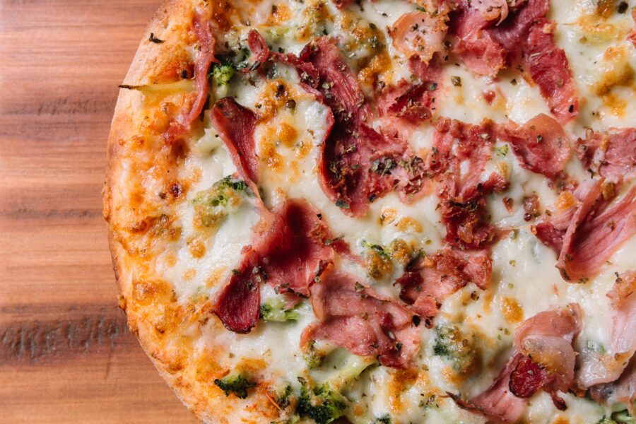 A high angle shot of a delicious California style pizza on a wooden surface