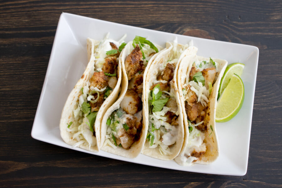 A plate of fish tacos topped with lime crema