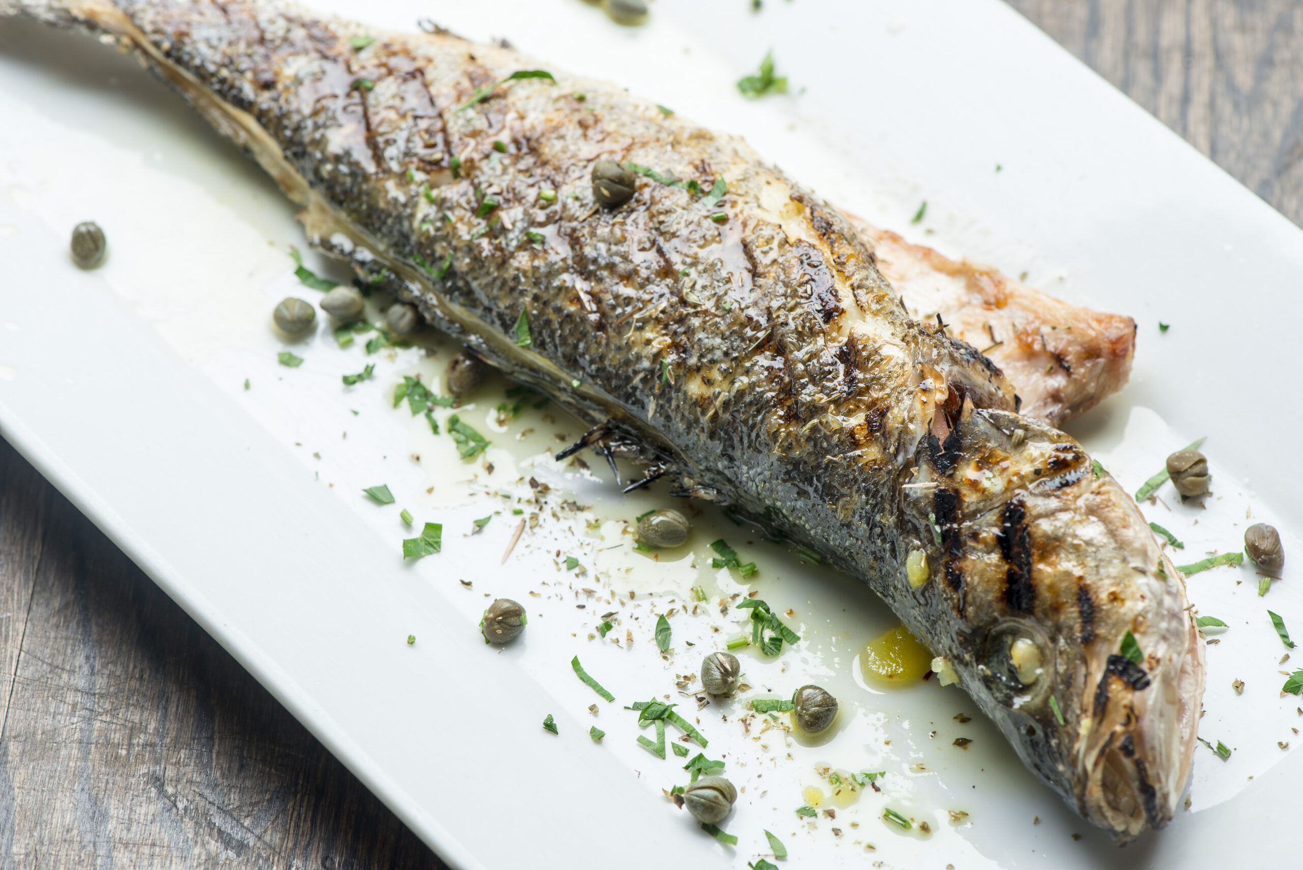 Branzino, whole grilled sea brim. Classic ethnic regional Greek seafood favorite. Whole fish, grilled with skin in, served with lemon potatoes lemons Italian parsley and capers.