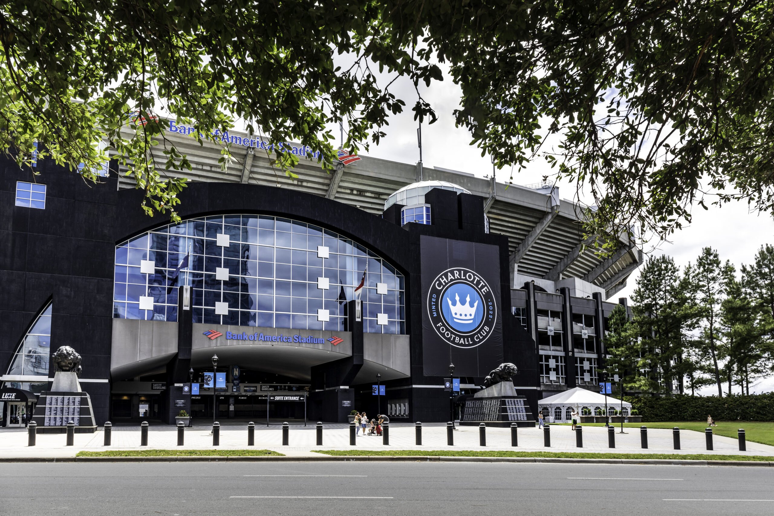 Charlotte, NC, USA-30 May 2021: Sign and logo at main entrance to the Carolina Panthers Bank of America Stadium. Logo of the Charlotte Football Club. People. Entrance framed by spring foliage.