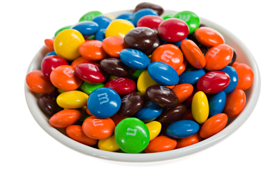 A white bowl full of multicolored m&m candies.