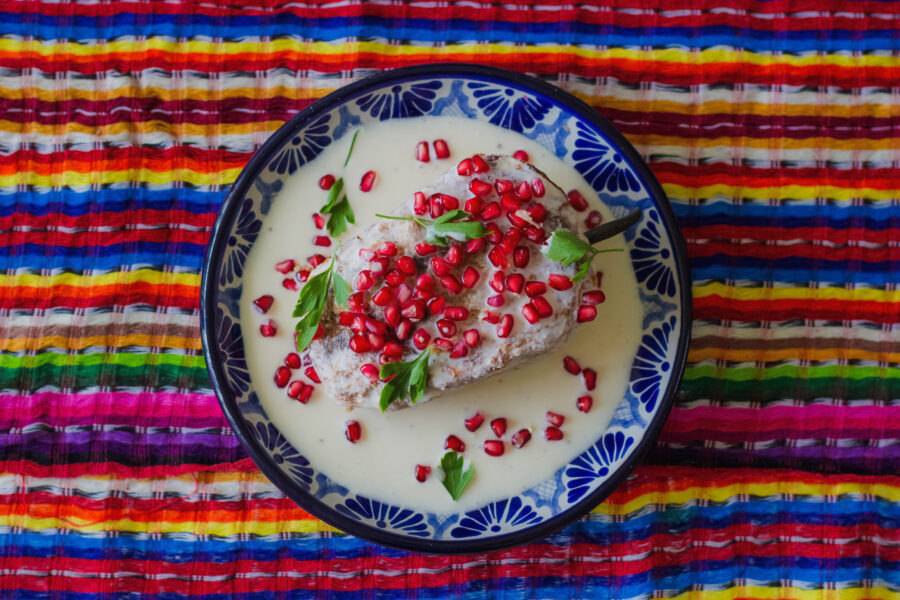 Chile in nogada in Talavera poblano dish with Mexican colors background