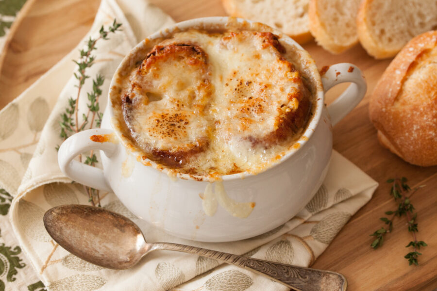 Crock of French Onion Soup with bread slices, spoon and fresh thyme