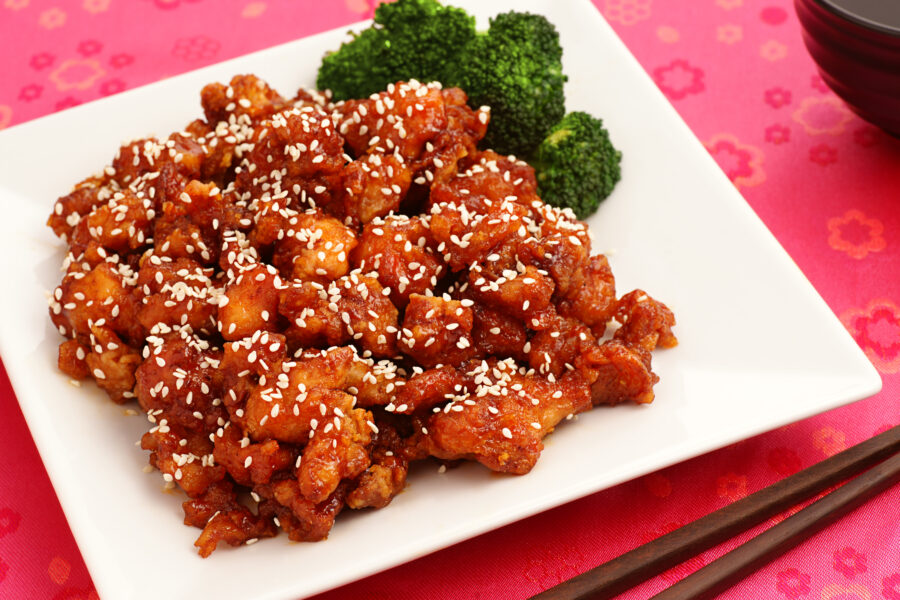 sesame chicken with broccoli on a white plate 