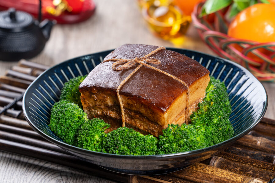 Dong Po Rou (Dongpo pork meat) in a beautiful blue plate with green broccoli vegetable, traditional festive food for Chinese new year cuisine meal, close up.