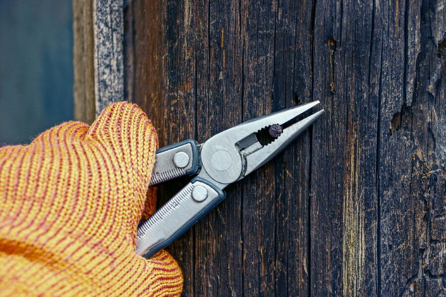 gloved hand holding pliers