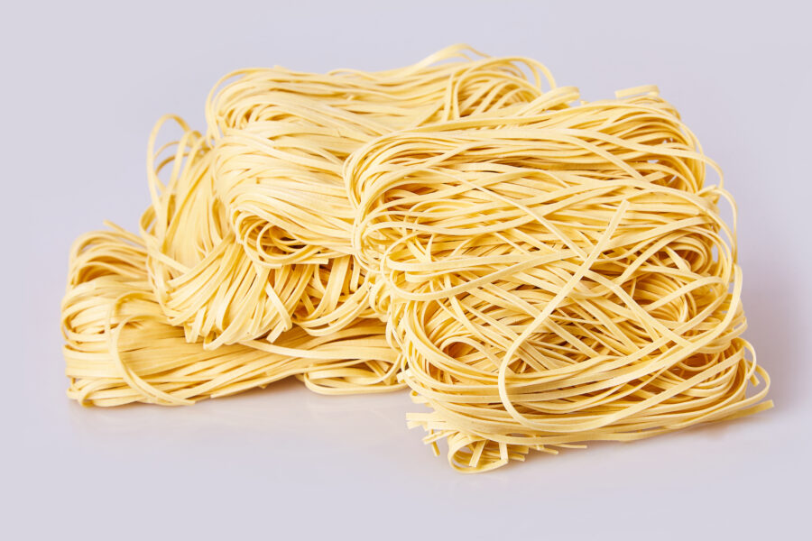 Dry thin rolled noodles square shape. Capelli d'angelo, Angel's hair - pasta.  Homemade Italian pasta tagliatelle. Italian Cuisine. Egg noodles. Pasta tagliatelle nest isolated on white background