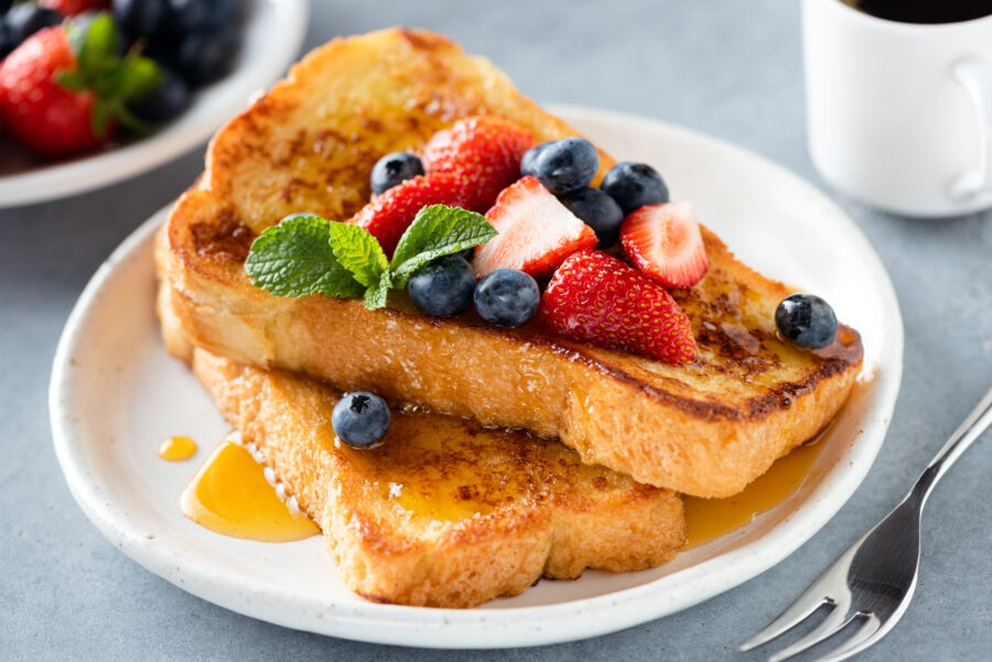 French toast with honey and berries on plate.