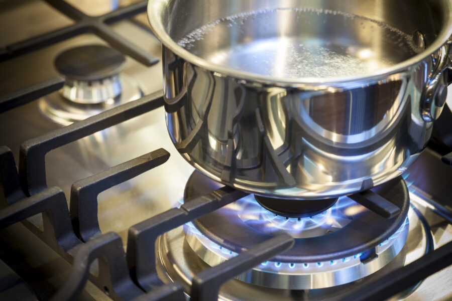 Gas burner on stove with flame on stainless steel surface showing heat ready for cooking food. 