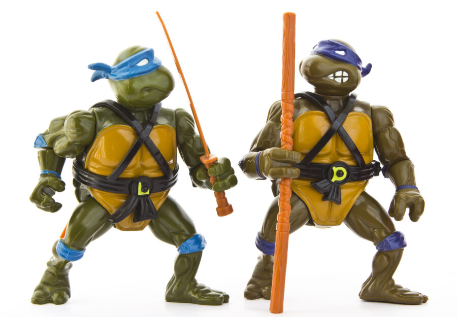 An isolated studio shot of two old action figures based on the Teenage Mutant Ninja Turtles franchise.