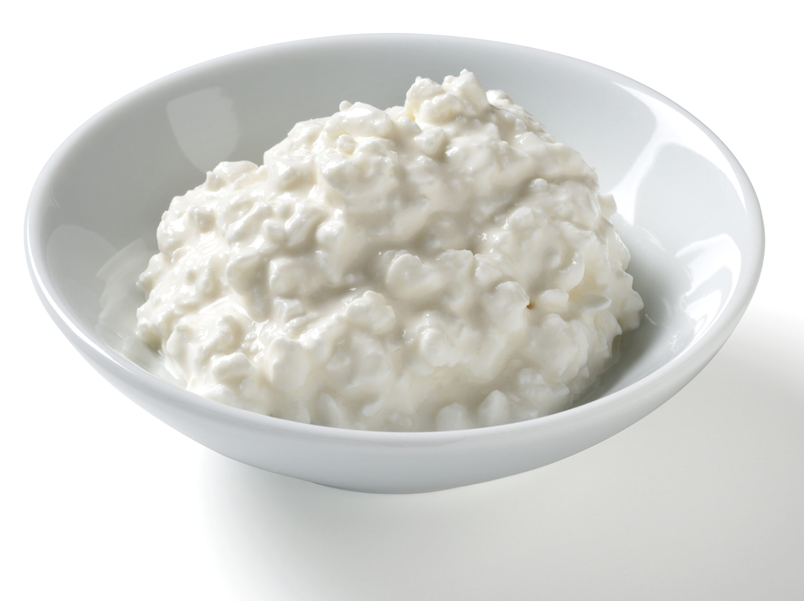 Half cup serving of low fat cottage cheese in a bowl on a white background with natural shadow.
