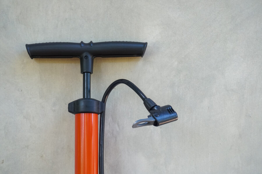 Hand air pump for motorcycle and bicycle tires in orange on a gray wall