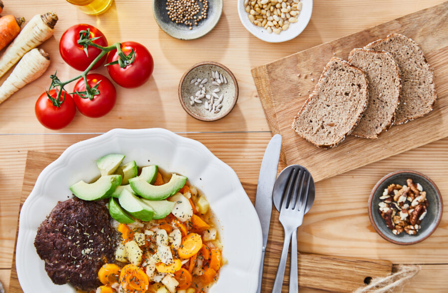 Healthy protein lunch, made of vegetable soup, beef meat, avocado, seeds and cherry tomatoes, served in a modern plate on a home wooden table top, representing a healthy lifestyle and wellbeing, an image with a copy space