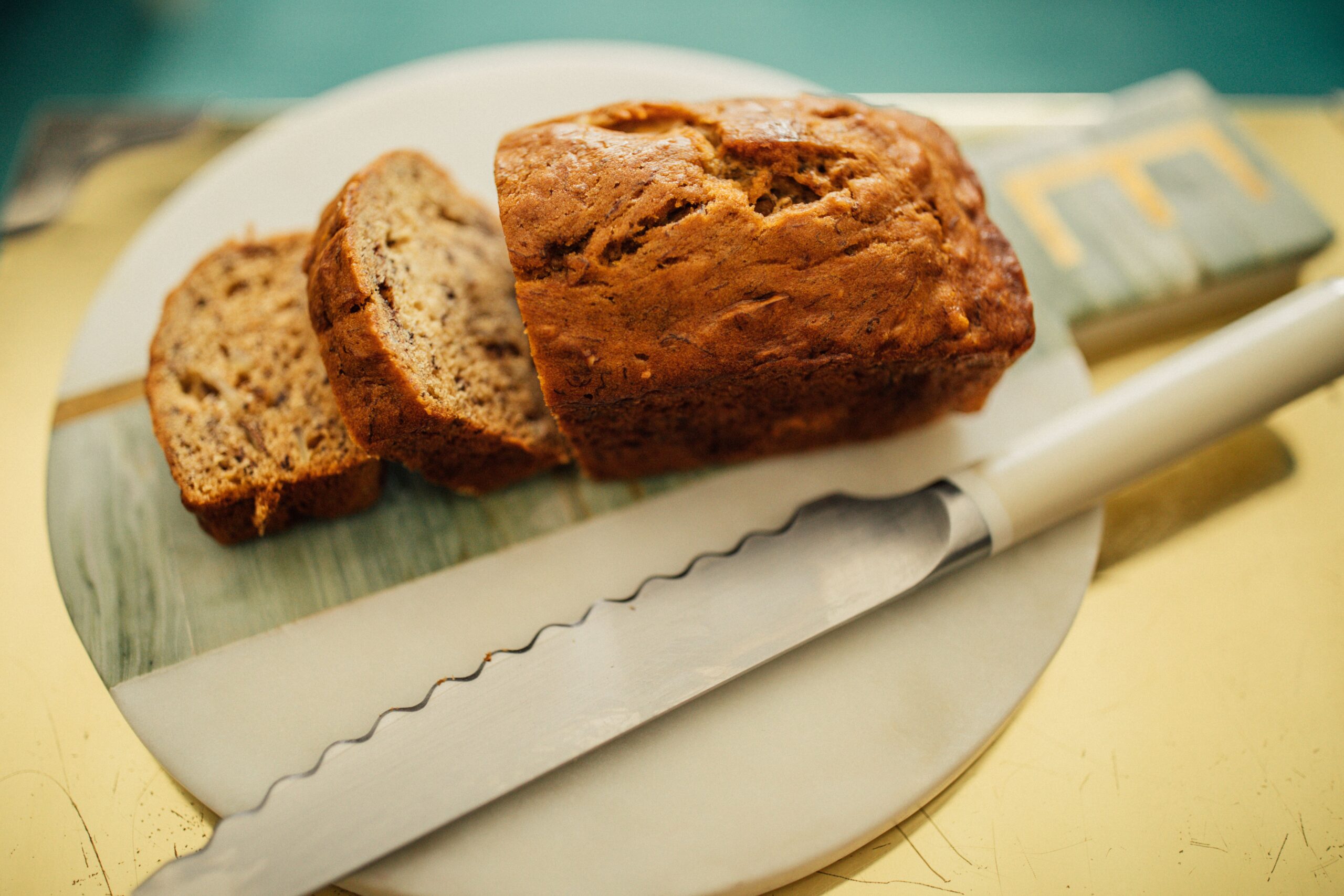 high angle view of sliced mini loaf of banana almond bread on marble, brass gold with serrated knife