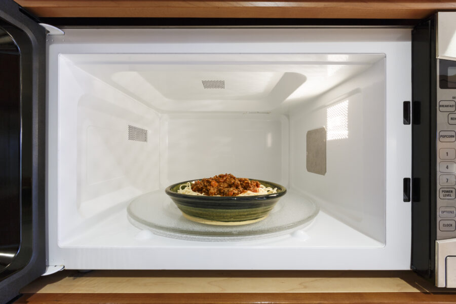 reheating plate of cooked spaghetti pasta with Bolognese tomato meat sauce in microwave oven