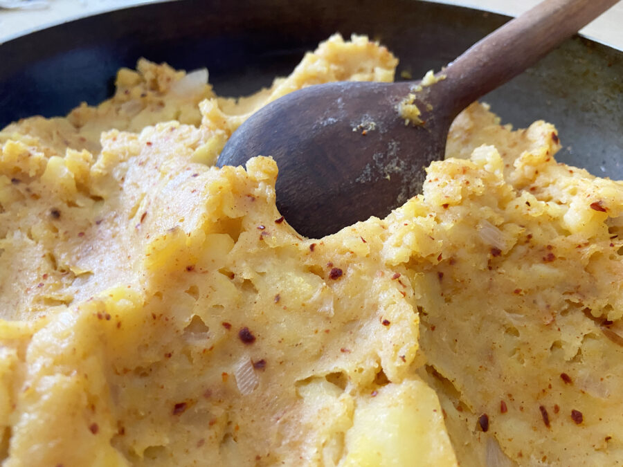 Mashed potatoes in the cooking pan with wooden spoon