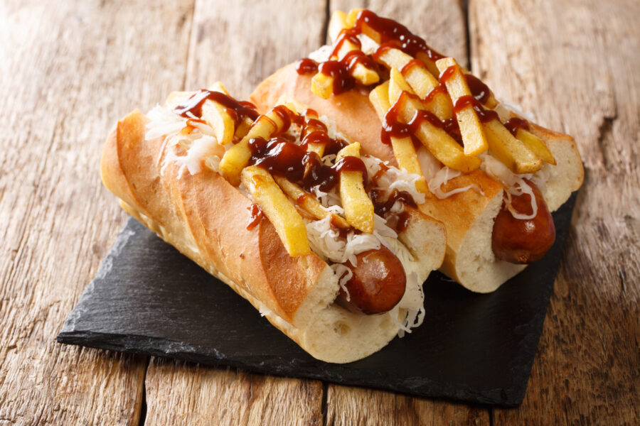 Polish boy's sandwich with sausage, cabbage salad, fries and barbecue sauce close-up on the table. horizontal