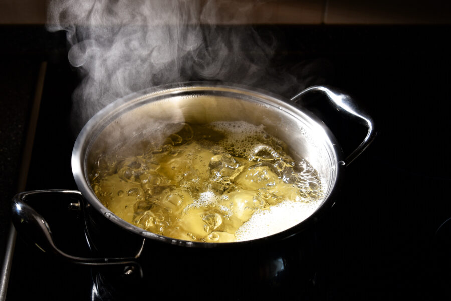 Potatoes boil in a saucepan on the stove