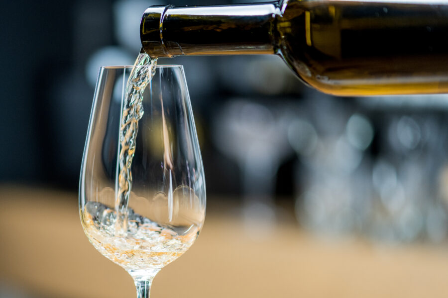 Pouring glass of wine. Serving white wine in transparent wine glass. 