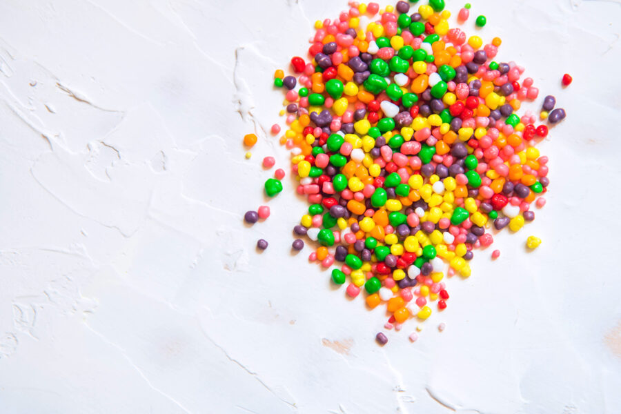 Rainbow colored candy nerds sprinkled on a white background.