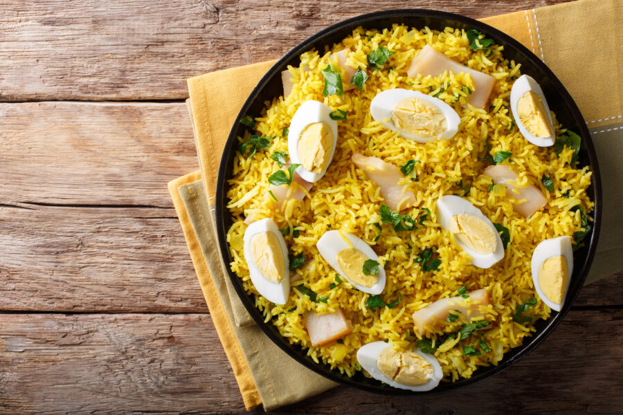 Tasty homemade Kedgeree with fish, boiled eggs, cilantro close-up on a plate on a table. horizontal top view from above
