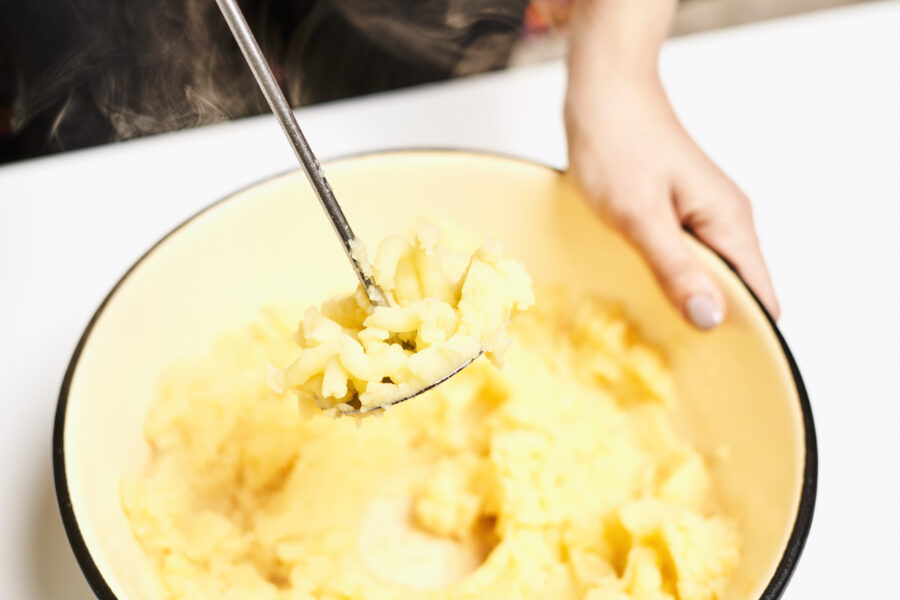 The female hands mashing potato with a masher