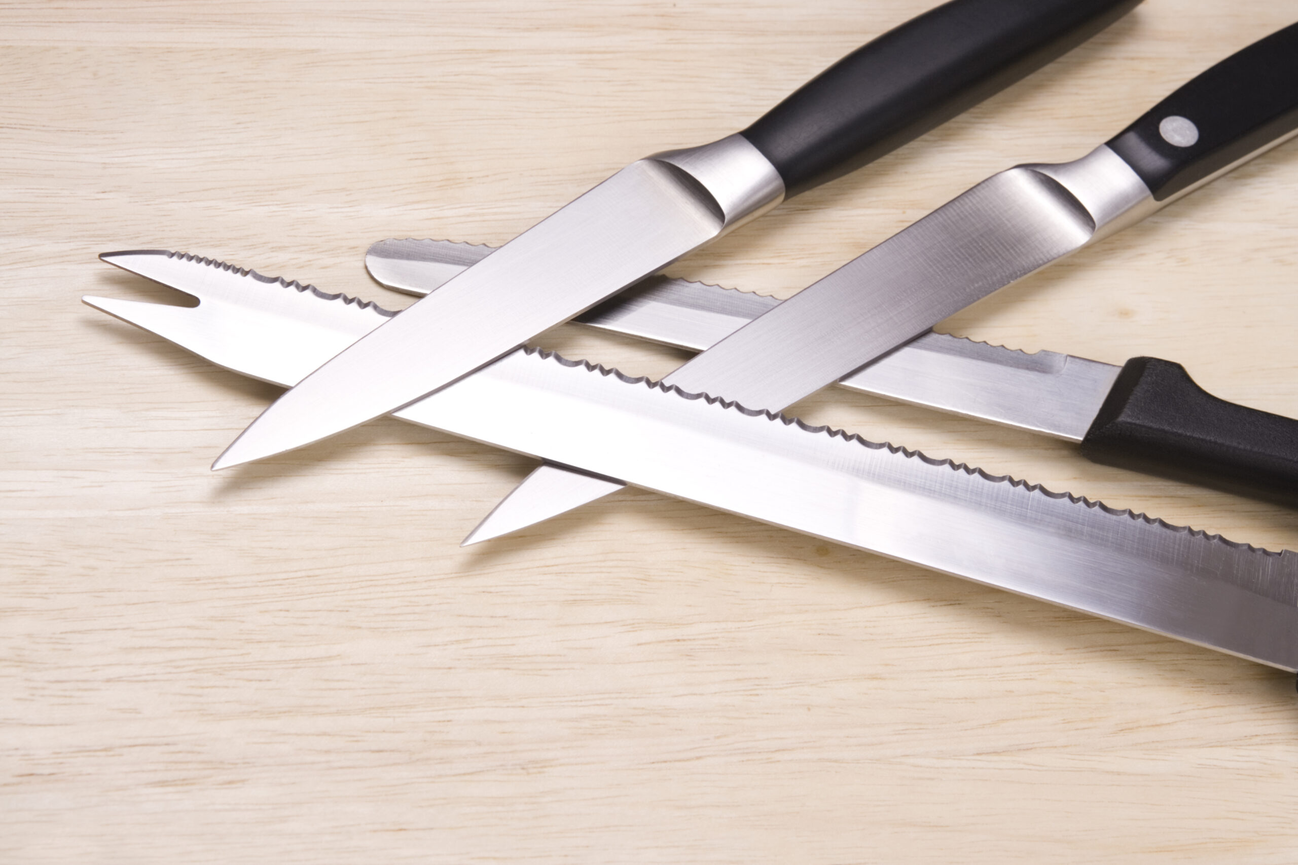 "Two paring knives, a bread knife and a steak knife arranged on a wooden cutting board. Similar:"