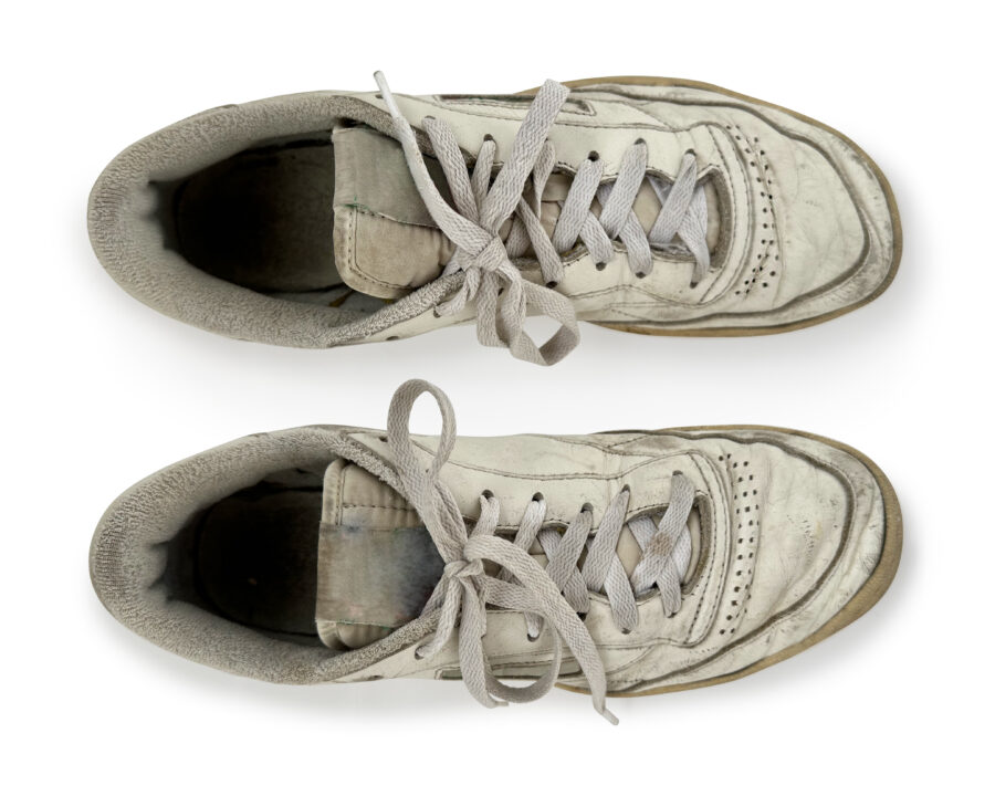 Various angles of a pair of  old vintage generic leather sneakers in heavily worn out condition. Clear-cut on a white seamless background