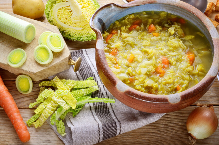 Vegetable soup in the tureen and ingredients.