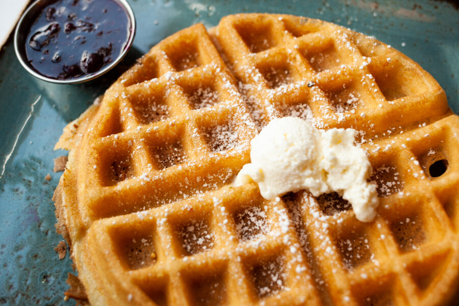 Waffle with powdered sugar, butter, mixed berry jam